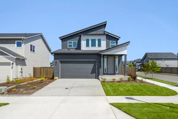Modern two-story gray house with a double garage, neatly landscaped front yard, and driveway at 8734 S 1st St in Greely Farms, set in a suburban neighborhood under a clear blue sky.