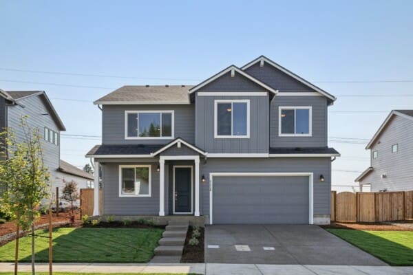 A modern two-story gray house with white trim on Metolius Ave features a double garage, multiple windows, a small covered entryway, steps to the front door, and a neatly landscaped front yard in the desirable Timber Grove neighborhood.